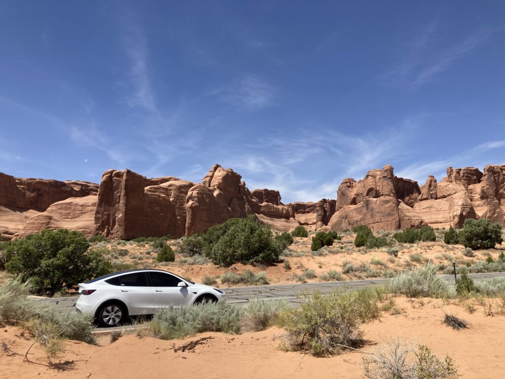 White Model Y Tesla parked in front of scenic mountains